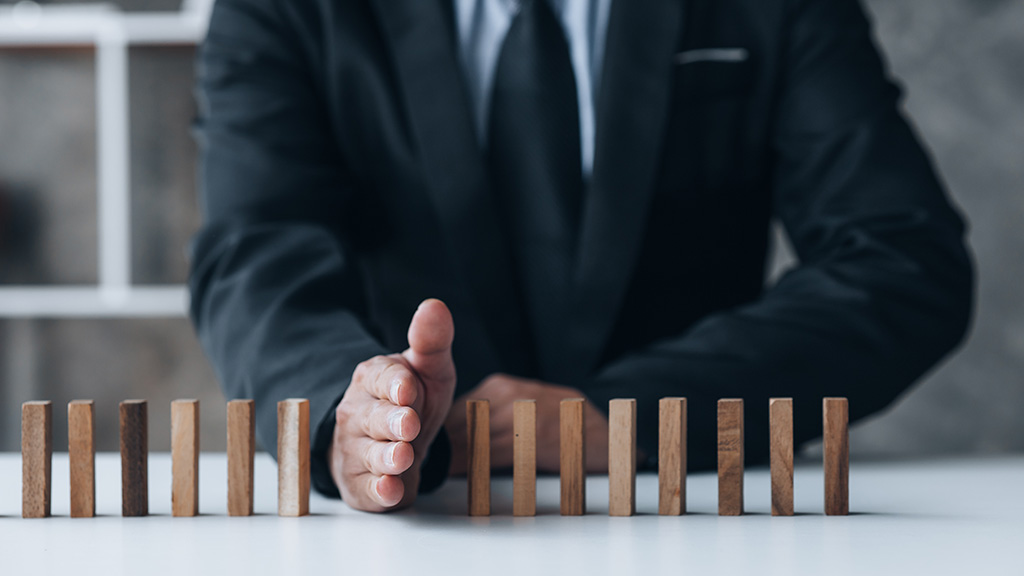 Nahaufnahme eines Geschäftsmannes, der Holzklötze in einer Reihe hält. Die Holzklötze symbolisieren das Risikomanagement im Unternehmen. Freiraum für Text.